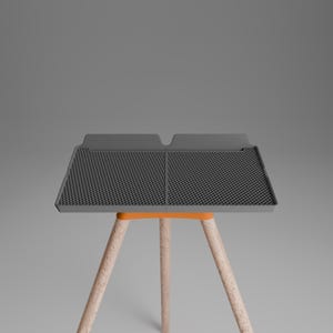 Peut inclure: Un tapis de s&eacute;chage rectangulaire en silicone gris fonc&eacute; avec une surface &agrave; grille textur&eacute;e et un bord sur&eacute;lev&eacute;, soutenu par un cadre orange et trois pieds en bois clair. Le tapis pr&eacute;sente une s&eacute;paration centrale et deux sections distinctes.