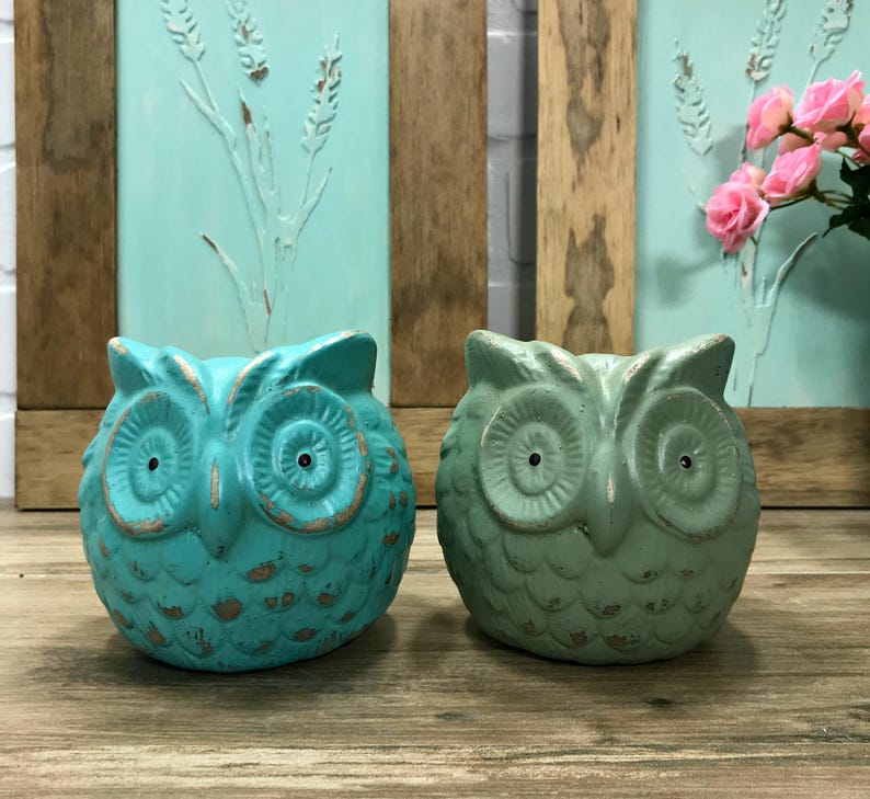 Puede incluir: Dos figuritas de b&uacute;ho de cer&aacute;mica azul verdoso con pintura desgastada. Los b&uacute;hos tienen ojos grandes y un dise&ntilde;o detallado.
