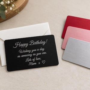 May include: A black rectangular metal card with rounded corners featuring the engraved white text Happy Birthday! Wishing you a day as amazing as you are. Lots of love, Mum x and a heart symbol, accompanied by a white envelope and three blank metal cards.