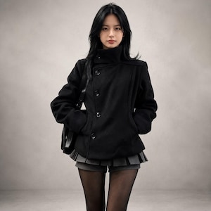 May include: A black wool-blend pea coat featuring a high collar, long sleeves, and a front button closure. The coat is paired with a dark grey pleated mini skirt and sheer black tights. A black shoulder bag is visible on the side of the garment.