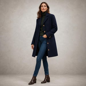May include: A navy blue wool-blend coat with a notched lapel and four visible buttons, worn over a dark green turtleneck sweater, dark blue denim jeans, and brown leather ankle boots with a block heel and a side zipper closure.