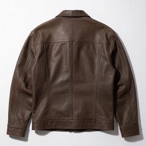 May include: A dark brown leather jacket featuring a classic collar, long sleeves with buttoned cuffs, and a straight hemline. The back panel displays vertical seam detailing, a horizontal yoke across the shoulders, and a smooth, matte finish.