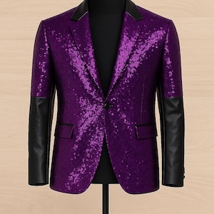 Puede incluir: Un blazer de lentejuelas morado con mangas y cuello de cuero negro, exhibido en un maniquí. La chaqueta de un solo pecho tiene un cierre de un botón y dos bolsillos delanteros. El fondo es de vetas de madera clara.