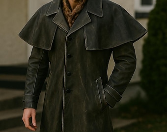 May include: A dark green, long coat with a cape-like shoulder design. The coat has a button-up front, pockets, and a collar. A brown scarf is visible at the neck. The coat appears to be made of a distressed leather material.