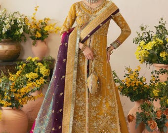 May include: Mustard yellow embroidered formal wear ensemble with a matching dupatta. The outfit features intricate gold embroidery, a wide-leg palazzo pant, and a small matching purse. The dupatta is a sheer fabric with a purple and teal pattern.