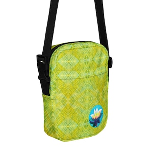 May include: A small, rectangular crossbody bag with a black strap and buckle. The bag features a vibrant yellow and green diamond pattern. A circular patch with a lotus flower design is on the front.