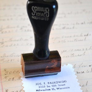 Könnte beinhalten: Ein schwarzer Vintage-Stempel von Schwaco Idealco Milwaukee mit Holzsockel. Der Stempel ist auf weißem Papier mit der Adresse von Jos. F. Palkowski, 3233 So. 15th Street, Milwaukee 15, Wisconsin, abgedruckt.