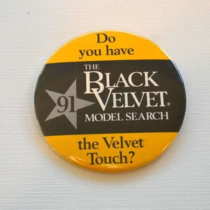 Puede incluir: Un botón redondo amarillo y negro con el texto "Do you have the Black Velvet Model Search the Velvet Touch?" El botón presenta una estrella negra con el número 91 en su interior.