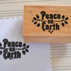 Timbro in gomma montato su legno con citazione "Pace sulla Terra"