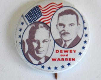 May include: A vintage campaign button featuring portraits of two men, with an American flag and the words "DEWEY and WARREN." The button is white with blue stars and a pin on the back.