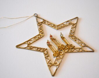 May include: Gold star-shaped ornament with a delicate filigree design. The star features a central motif of three candles with red and white accents.