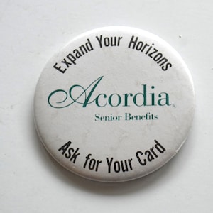 May include: A circular white pinback button featuring black text that reads Expand Your Horizons at the top and Ask for Your Card at the bottom. In the center, the word Acordia is printed in a dark green script font above Senior Benefits.