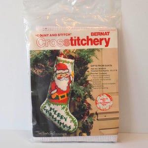 May include: A cross stitch kit featuring a Santa Claus stocking with the words "Merry Christmas" on it. The kit includes fabric, yarn, a needle, and instructions. The finished stocking is approximately 25 cm by 46 cm.