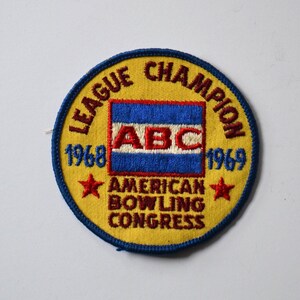 May include: A yellow and blue embroidered patch with the text "League Champion 1968-1969" and "American Bowling Congress". The patch also features a blue, white, and red flag with the letters "ABC" in the center.