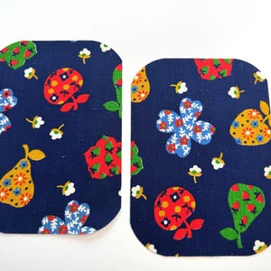 May include: Two navy blue fabric patches with rounded corners. The patches feature a repeating pattern of colorful flowers, pears, and other botanical elements. The design includes red, white, yellow, and green details.