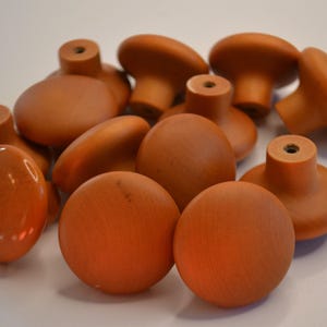 May include: A group of 11 wooden knobs in a warm brown color. The knobs are round and have a smooth finish.