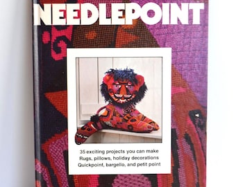 May include: A vintage "Better Homes and Gardens" needlepoint book. The cover displays the title in white block letters and an image of a colourful needlepoint lion. The book promises 35 exciting projects, including rugs, pillows, and holiday decorations.