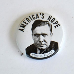 May include: A vintage white button featuring the text "AMERICA'S HOPE" in black, surrounding a black and white portrait of Wendell Willkie. The name "WENDELL WILLKIE" is printed in a white rectangle at the bottom.