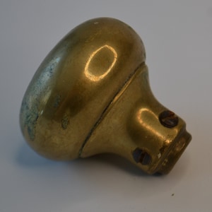 May include: A brass door knob with a rounded top and a slightly worn finish.