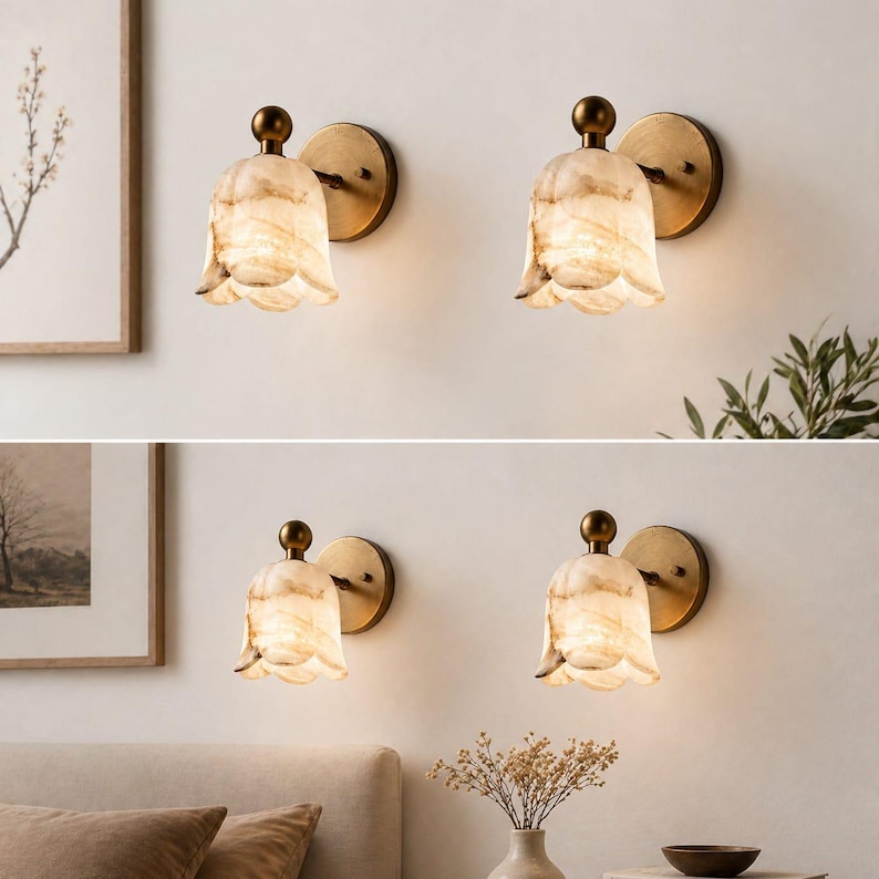 May include: Four wall sconces with a floral design. Each sconce features a cream-colored, petal-shaped shade with a marbled effect, a brass-colored backplate, and a small, round brass finial. The sconces are mounted on a light-colored wall.