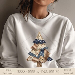 May include: White sweatshirt featuring a patchwork Christmas tree design. The tree is composed of various fabric patterns, including floral, striped, and dotted prints, with blue and white star-patterned accents. A button detail is at the base of the tree.