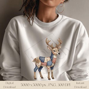 May include: White sweatshirt with a deer design featuring patriotic patchwork patterns. The deer has antlers and is decorated with stars and stripes, creating a vintage Americana look. The sweatshirt is a comfortable, casual style.