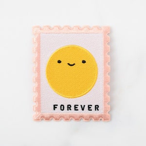 May include: A pink and white embroidered patch with a yellow smiling sun and the word "FOREVER" in black.