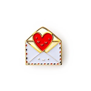 May include: Gold-tone enamel pin featuring a red heart with a smiling face inside a white envelope with a smiling face. The envelope has a blue and red striped border.