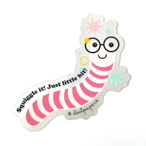 May include: A pink and white striped worm with glasses and a happy face. The worm is wearing a crown of stars and has the text "Squiggle it! Just little bit!" and "@ilootpaperie" on it.