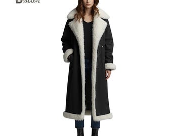 May include: A long black coat with a white faux fur collar, cuffs, and trim. The coat is buttoned up and worn by a person. The coat is a classic style, suitable for cold weather.