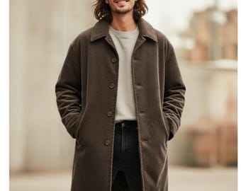 Può includere: Un cappotto di velluto a coste marrone con chiusura a bottoni e collo. Il cappotto è indossato sopra una felpa girocollo grigio chiaro e jeans neri. Il cappotto ha una vestibilità ampia e maniche lunghe.