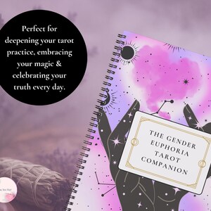 May include: A notebook with a spiral binding, decorated with a celestial design of a pink and purple nebula, stars, and a crescent moon. A card with the text "THE GENDER EUPHORIA TAROT COMPANION" is in front. The background is a soft lavender colour.