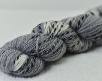 May include: A skein of gray yarn with white and black flecks. The yarn is tightly wound and has a soft, textured appearance. Ideal for knitting or crocheting projects.