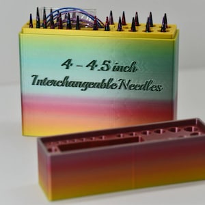 May include: A set of interchangeable knitting needles in a gradient box. The box is labeled "4 - 4.5 inch Interchangeable Needles". The needles are in a yellow, green, and red box, with a separate, smaller container.