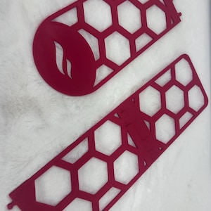 May include: Two red laser-cut wood pieces. One is a rounded shape with a flame design, and the other is a long, rectangular shape with a honeycomb pattern. The pieces are likely decorative or functional.
