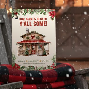 May include: A Christmas-themed poster with the text "OUR BARN IS DECKED Y'ALL COME!" is displayed on a wooden swing. The poster features a drawing of a barn decorated for Christmas. A red and black plaid blanket is draped over the swing.