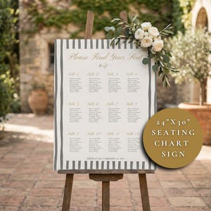 May include: A wedding seating chart sign on a wooden easel. The sign is 24" x 30" with a striped border and the words "Please Find Your Seat". The sign is decorated with flowers and greenery.