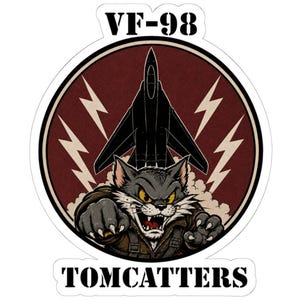 Puede incluir: Una pegatina circular con fondo rojo oscuro, la silueta de un avión de combate negro y cuatro rayos blancos. En primer plano, un gato de dibujos animados agresivo lleva una chaqueta de vuelo marrón. El texto dice VF-98 y TOMCATTERS.