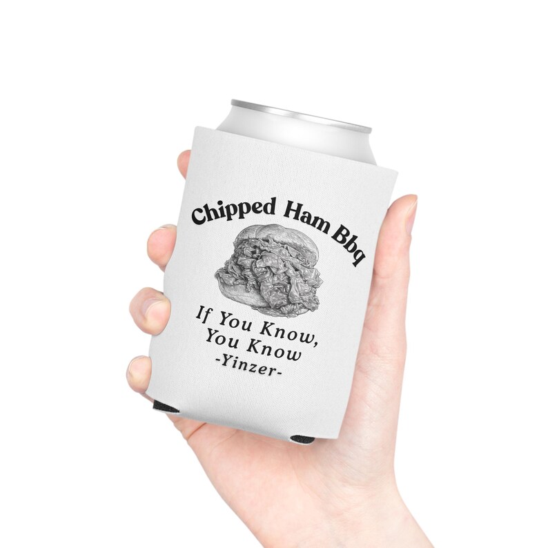 May include: A white foam can cooler featuring a black graphic of a chipped ham sandwich. The text reads Chipped Ham Bbq, If You Know, You Know, and -Yinzer- in a black serif font. The cooler is designed to fit a standard beverage can.