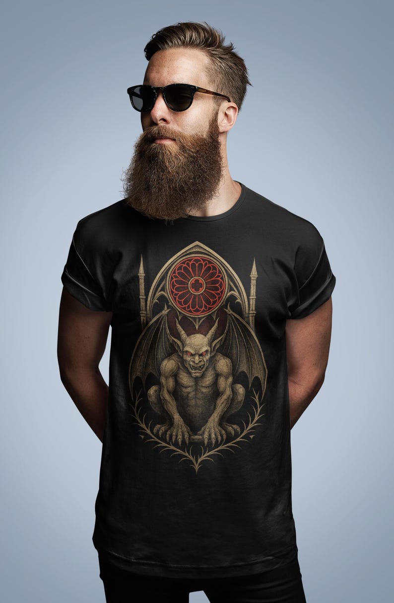 May include: Black t-shirt featuring a gothic gargoyle design. The graphic showcases a detailed, gray gargoyle with bat-like wings, perched in front of a stained-glass window. The window has a red circular design. The shirt is a crew neck style.