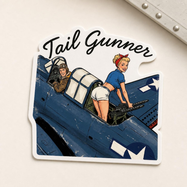 May include: A die-cut sticker featuring a blue military aircraft with the text Tail Gunner. The illustration shows a pilot in a cockpit and a person in a blue shirt and white shorts operating a machine gun mounted on the rear of the plane.