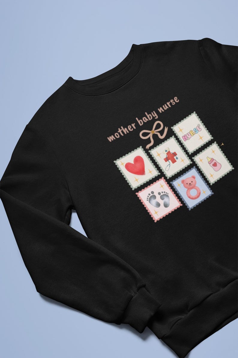 K&ouml;nnte beinhalten: Schwarzes Sweatshirt mit dem Text "mother baby nurse" und einer Schleifengrafik. Das Design umfasst Briefmarken-&auml;hnliche Bilder eines Herzens, Fu&szlig;abdr&uuml;cke, eines Teddyb&auml;ren, einer Babyflasche, eines Kreuzes und das Wort "nurse".