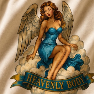 May include: A cream-colored sweatshirt featuring a graphic print of an angel with auburn hair, large wings, and a halo, wearing a blue strapless dress while sitting on clouds. A blue banner at the bottom displays the text HEAVENLY BODY in gold.