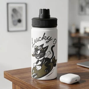 May include: White water bottle with a black lid and a cartoon graphic of a black cat riding a bomb, with the words "Lucky 13" in script. The cat wears goggles and holds a cigar. The bottle is on a wooden surface.