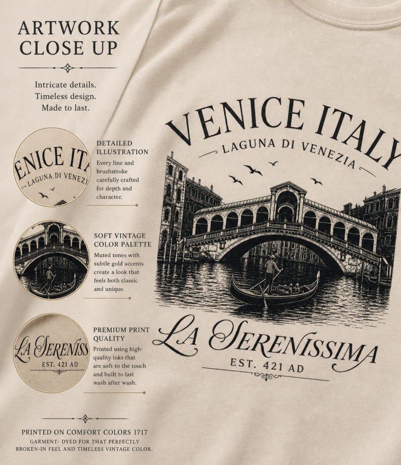 May include: A beige t-shirt featuring a black graphic illustration of the Rialto Bridge in Venice, Italy, with a gondolier in a boat. The text reads VENICE ITALY, LAGUNA DI VENEZIA, and LA SERENISSIMA EST. 421 AD, alongside descriptive marketing text.