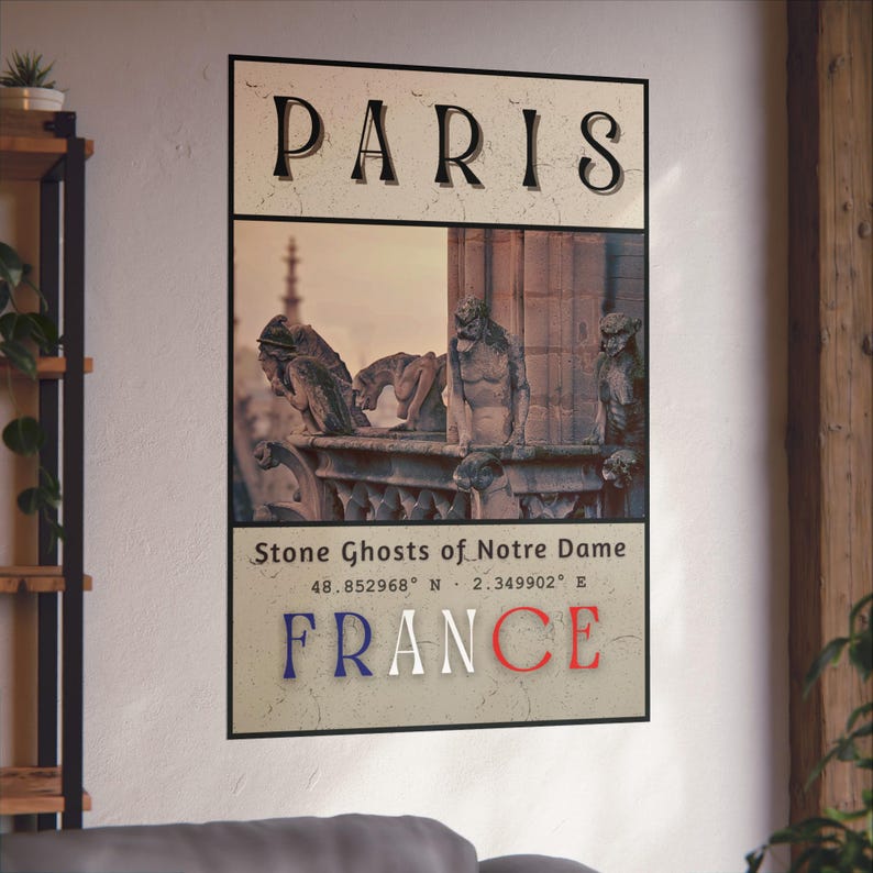 May include: A framed poster featuring the word "PARIS" at the top, with an image of Notre Dame's gargoyles. Below the image, it reads "Stone Ghosts of Notre Dame" and "FRANCE" in red, white, and blue. Coordinates are also included.