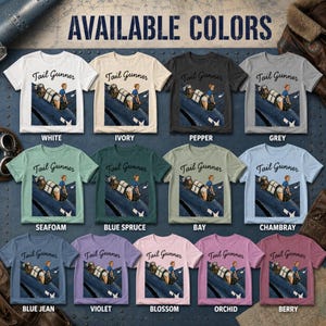 May include: A collection of thirteen short-sleeve t-shirts in various colors, each featuring a graphic of a person in a military aircraft turret with the text Tail Gunner. The colors include white, ivory, pepper, grey, seafoam, blue spruce, bay, chambray, blue jean, violet, blossom, orchid, and berry.
