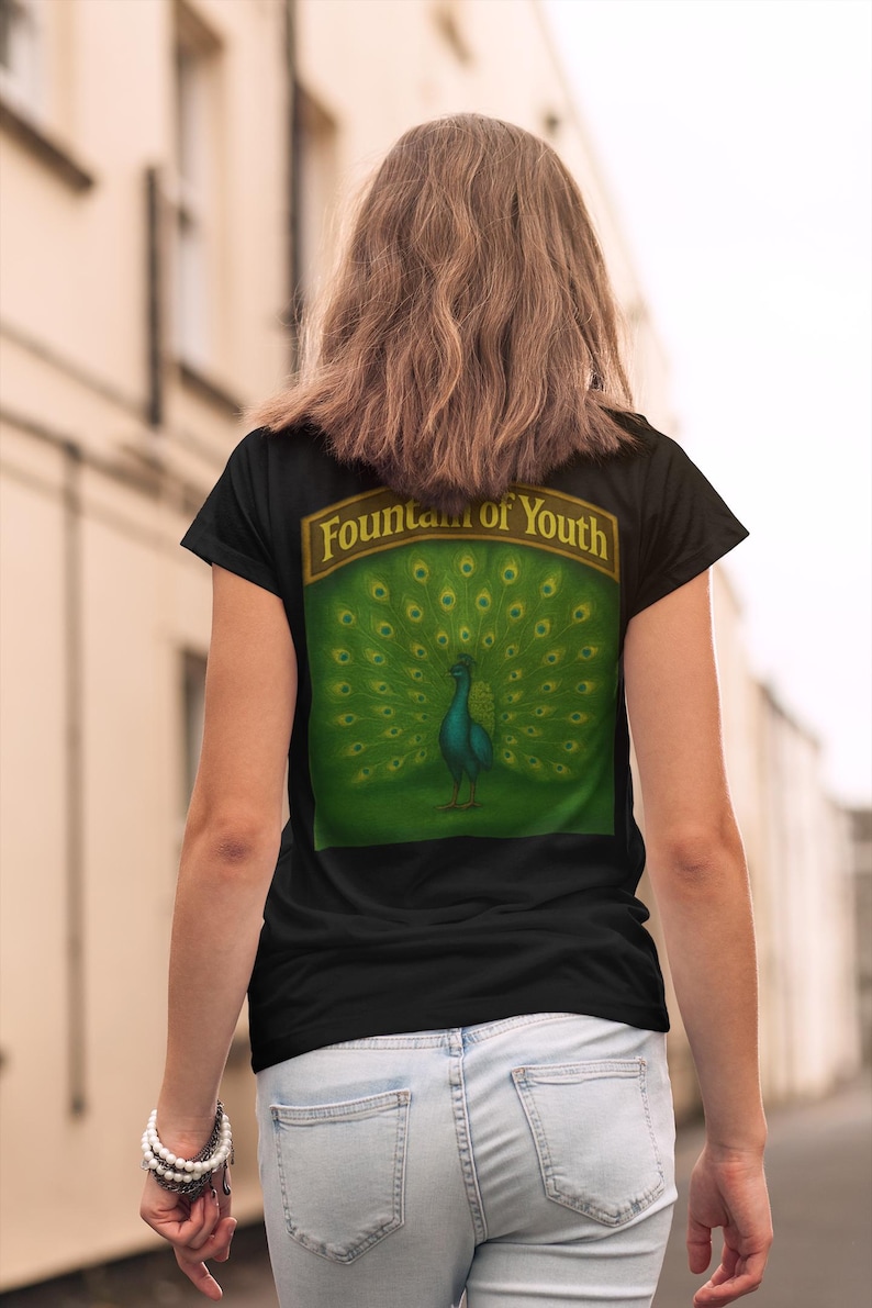 May include: Black t-shirt with a peacock design on the back. The peacock is teal with a green background and a banner that reads "Fountain of Youth". The shirt is worn with light blue jeans.
