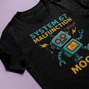 May include: Black t-shirt featuring a distressed graphic of a malfunctioning robot with the text "SYSTEM 67 MALFUNCTION" in teal and yellow. The robot is teal with red eyes and a yellow hazard symbol.