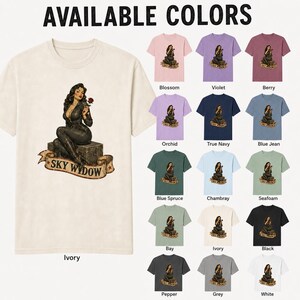 May include: An ivory short-sleeve t-shirt featuring a graphic of a woman in a black outfit sitting on a trunk holding a red rose with the text SKY WIDOW on a banner. The image displays a color chart of fifteen different t-shirt color options.